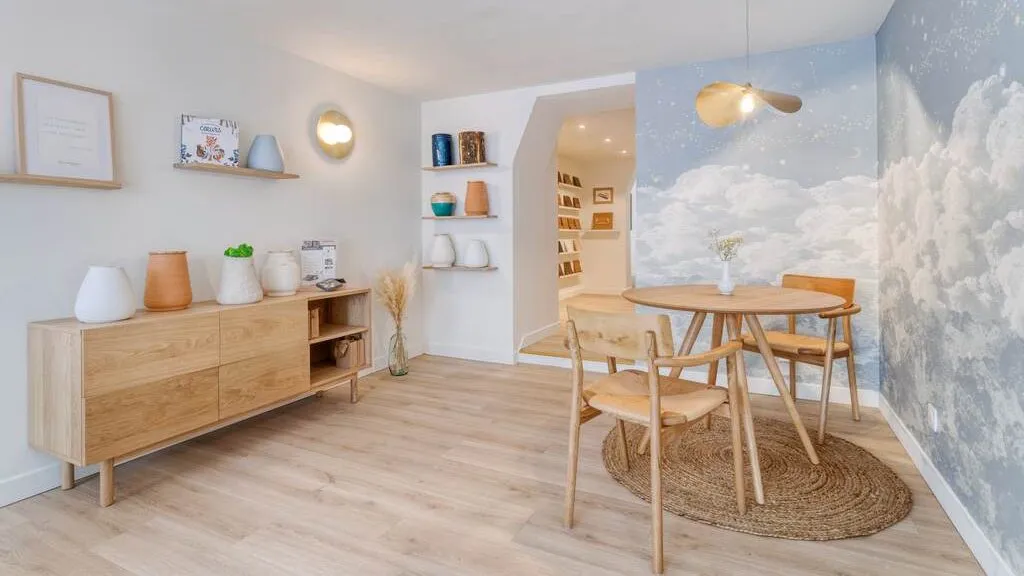 Espace de conseil en pompes funèbres lumineux avec mobilier en bois clair et papier peint nuages