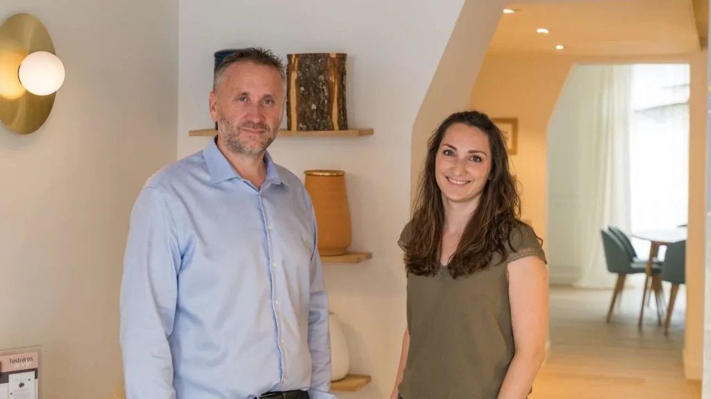 Portrait de deux conseillers funéraires souriants dans l'accueil chaleureux d'une agence d'obsèques