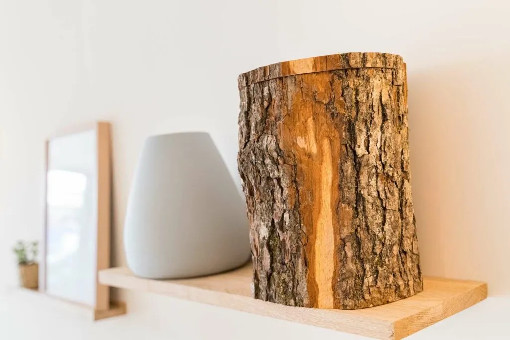 Gros plan sur une urne cinéraire écologique en bois naturel en forme de bûche sur une étagère murale
