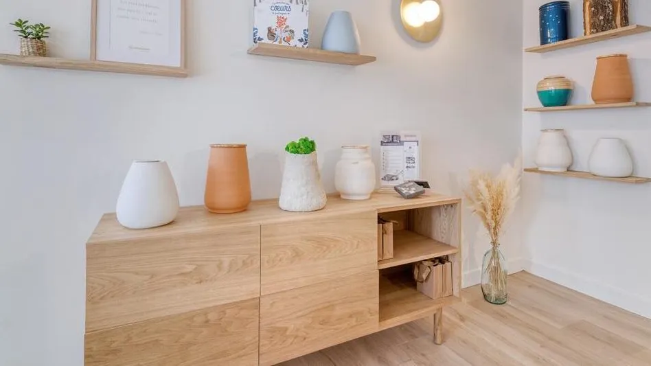 Meuble en bois d'agence funéraire présentant une sélection d'urnes cinéraires design et modernes